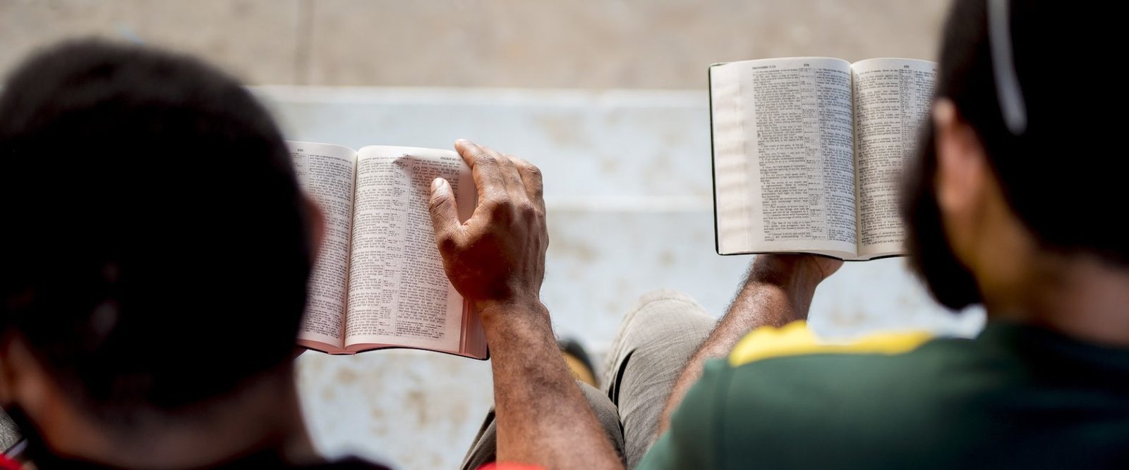 Overhead shot of people sitting and reading the bible with a blurred background